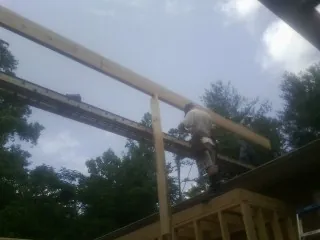 Carpenter setting a ridge beam over a new addition frame — Ice Dam Removal by Roofing Brothers in College Station