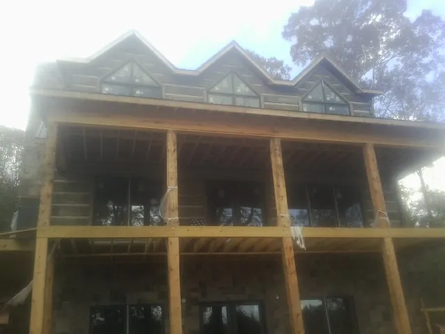 Dormers and porch framing on a large log home under construction — Roof Coating work by our crew in College Station