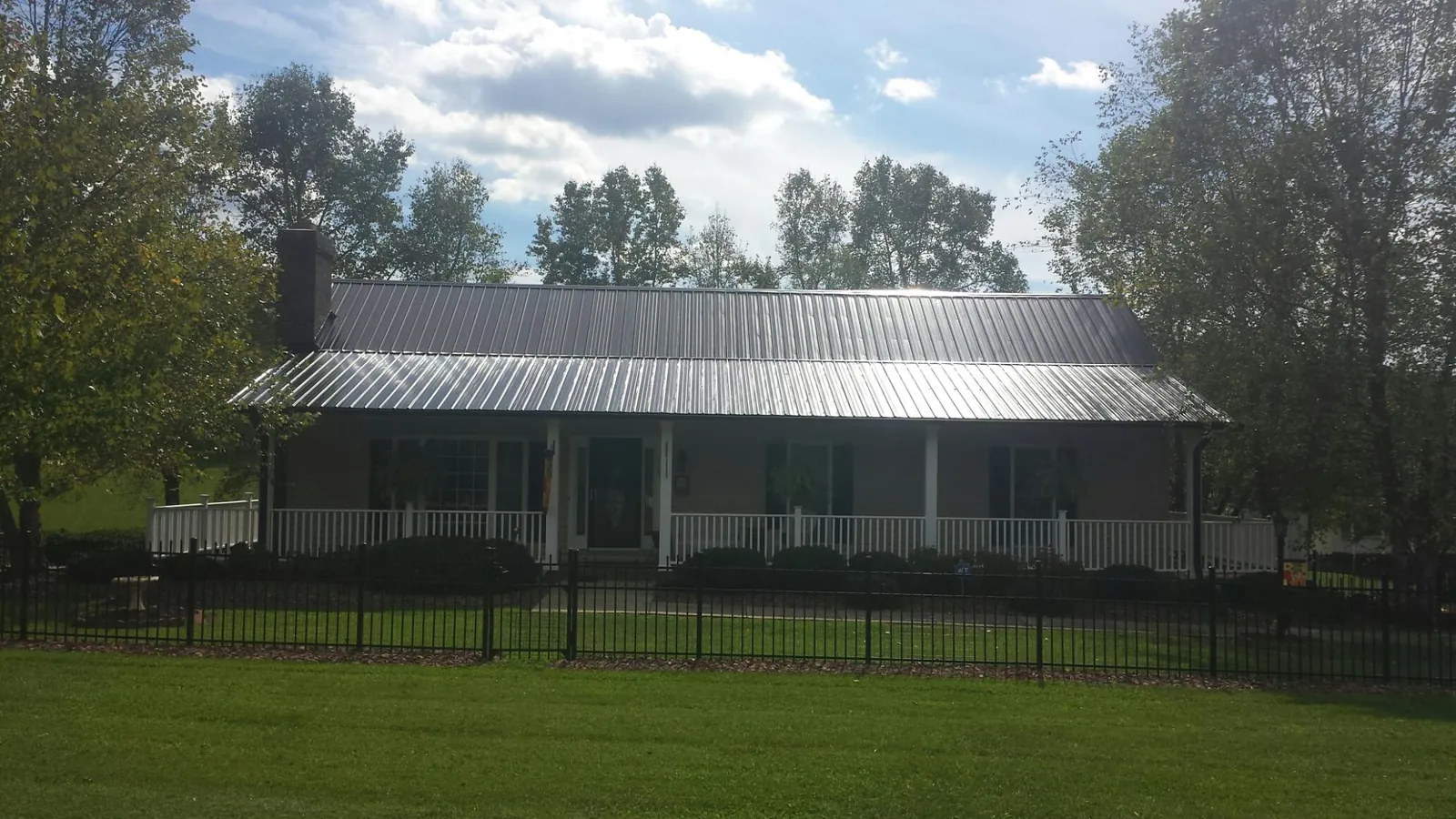 Gray metal roof on a brick ranch with a full width front porch — Gutter Guard Installation work by our crew in College Station